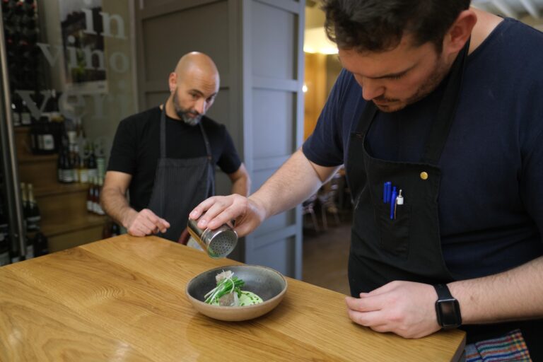 Benito Gómez observa la preparación de un plato por Daniel Moreno, jefe de cocina de Tragatá Málaga