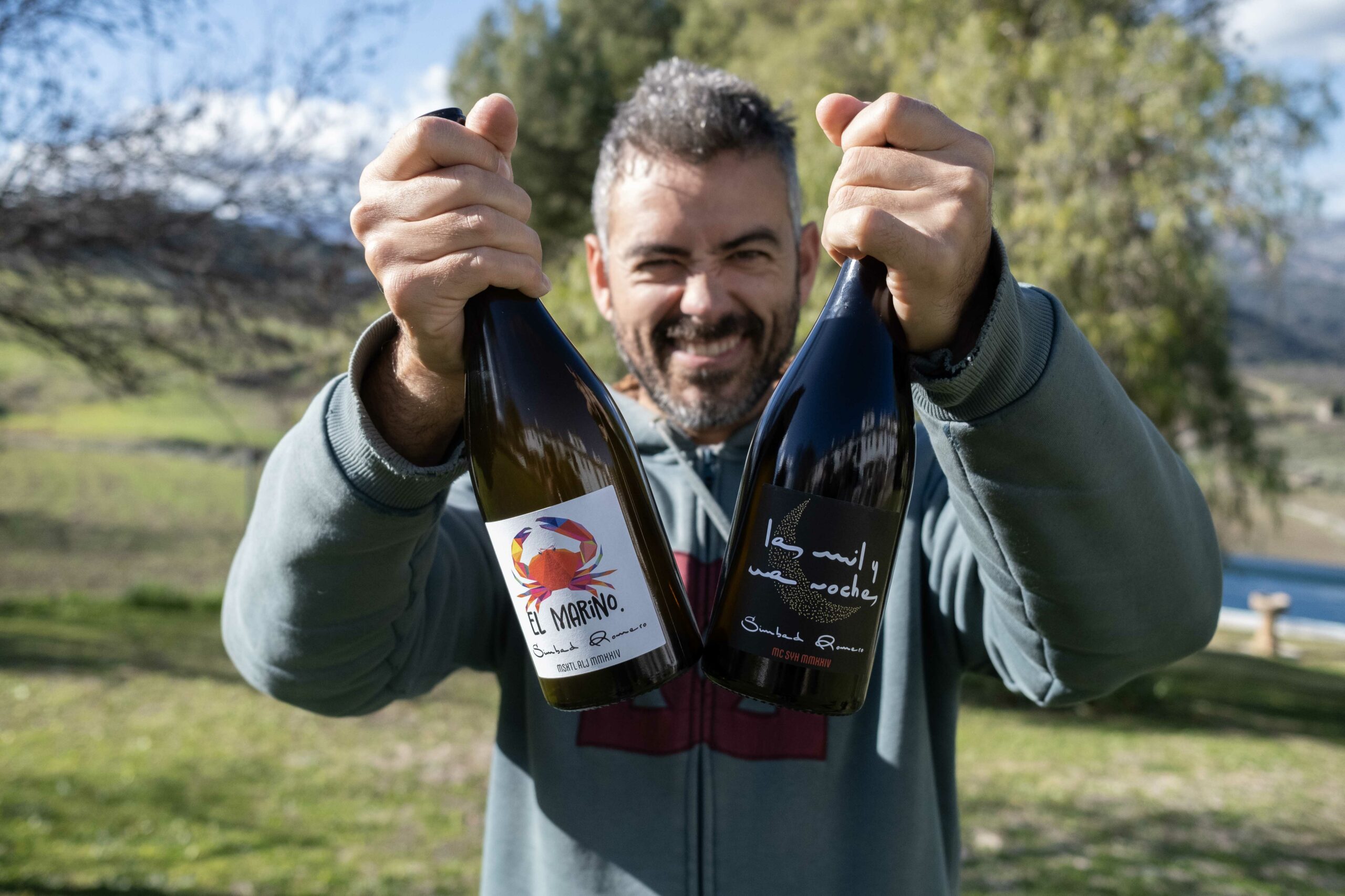 Simbad Romero mostrando dos de sus vinos.